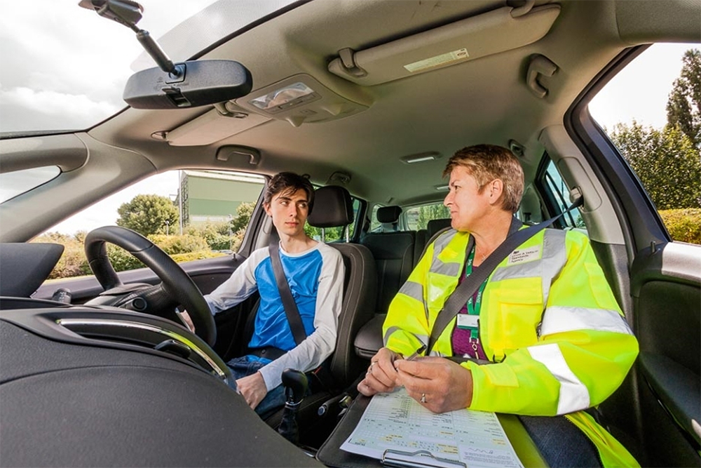A boy having his driving examination inside of a car